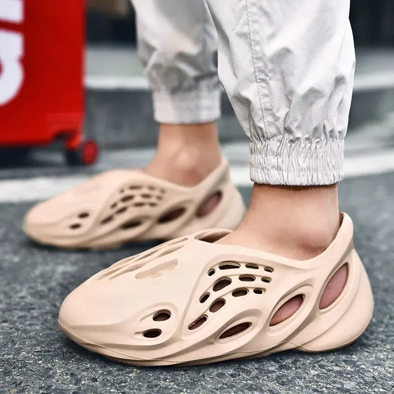 Beige slip-on foam clogs with ventilation holes, worn outdoors, modern fashion footwear