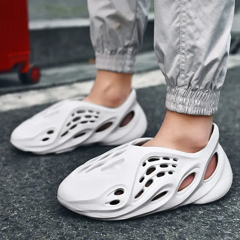 Person wearing white slip-on foam clogs with cutout design on city street