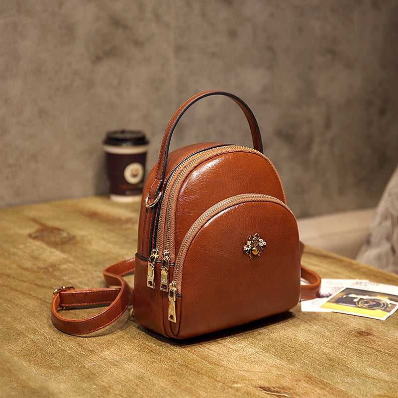 Undefyning Lynes brown oil wax leather convertible shoulder bag with a bee emblem and adjustable crossbody strap.